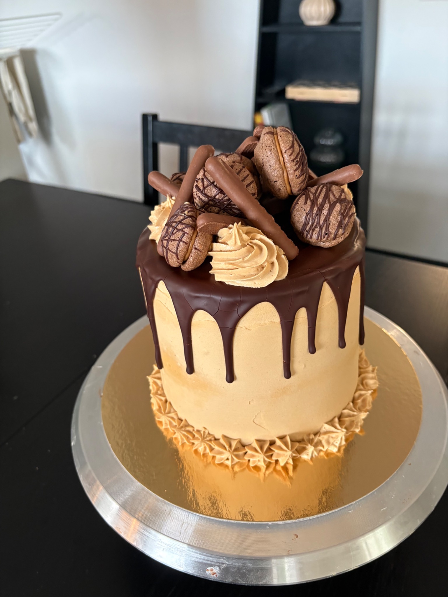 Golden buttercream cake with chocolate drips, biscuits and piped swirls