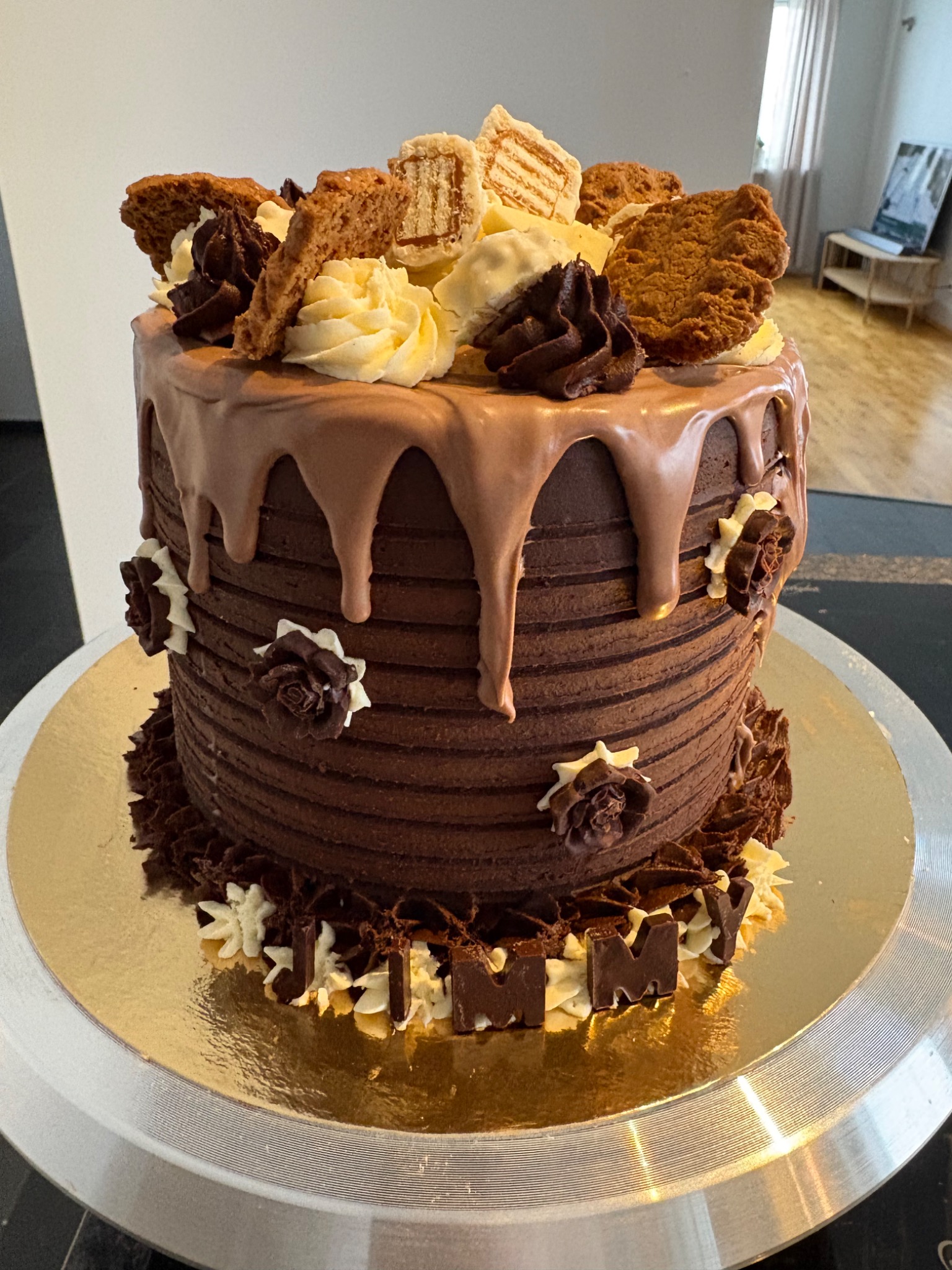 Chocolate cake with textured frosting, biscuit pieces and buttercream flowers