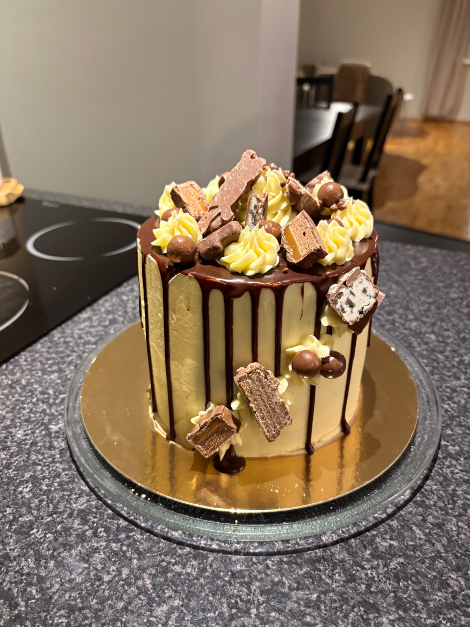 Tall cake with chocolate drips and a cascade of chocolate pieces
