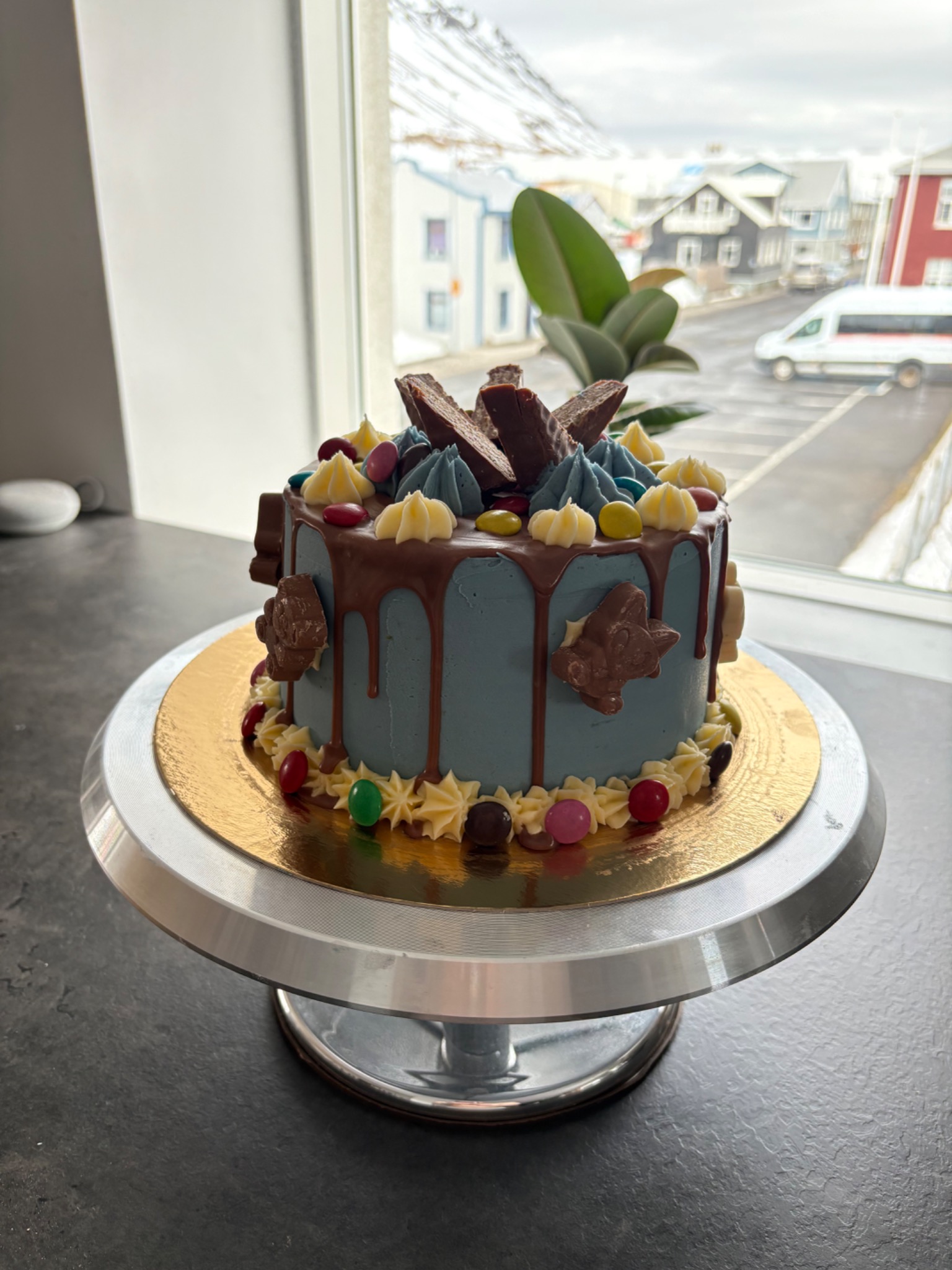 Blue celebration cake with colourful sweets and chocolate decorations